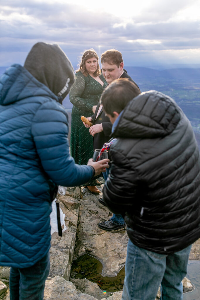 Mother and father of the bride help pour juice for communion to be taken during Shenandoah elopement