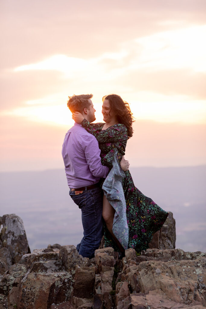 Bride-to-be’s dress flows in the wind as she embraces her fiancé atop Shenandoah’s Little Stony Man summit.