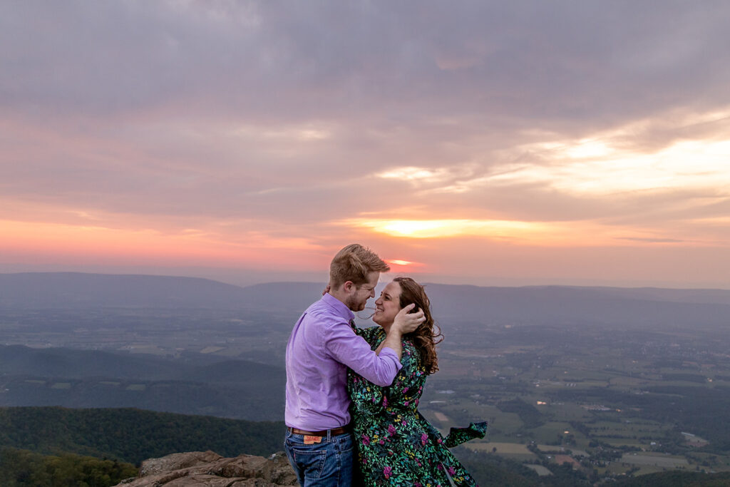 The couple shares a wind-swept embrace, the dramatic mountain scenery making the moment feel even more magical.