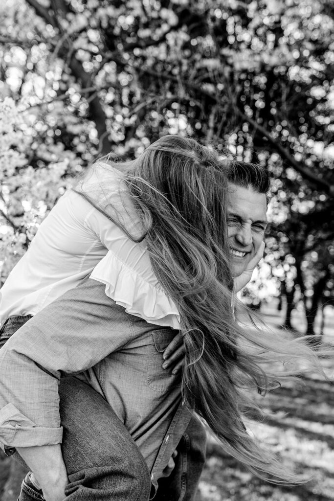 Couple laughing together during their Washington, DC engagement session under cherry blossoms