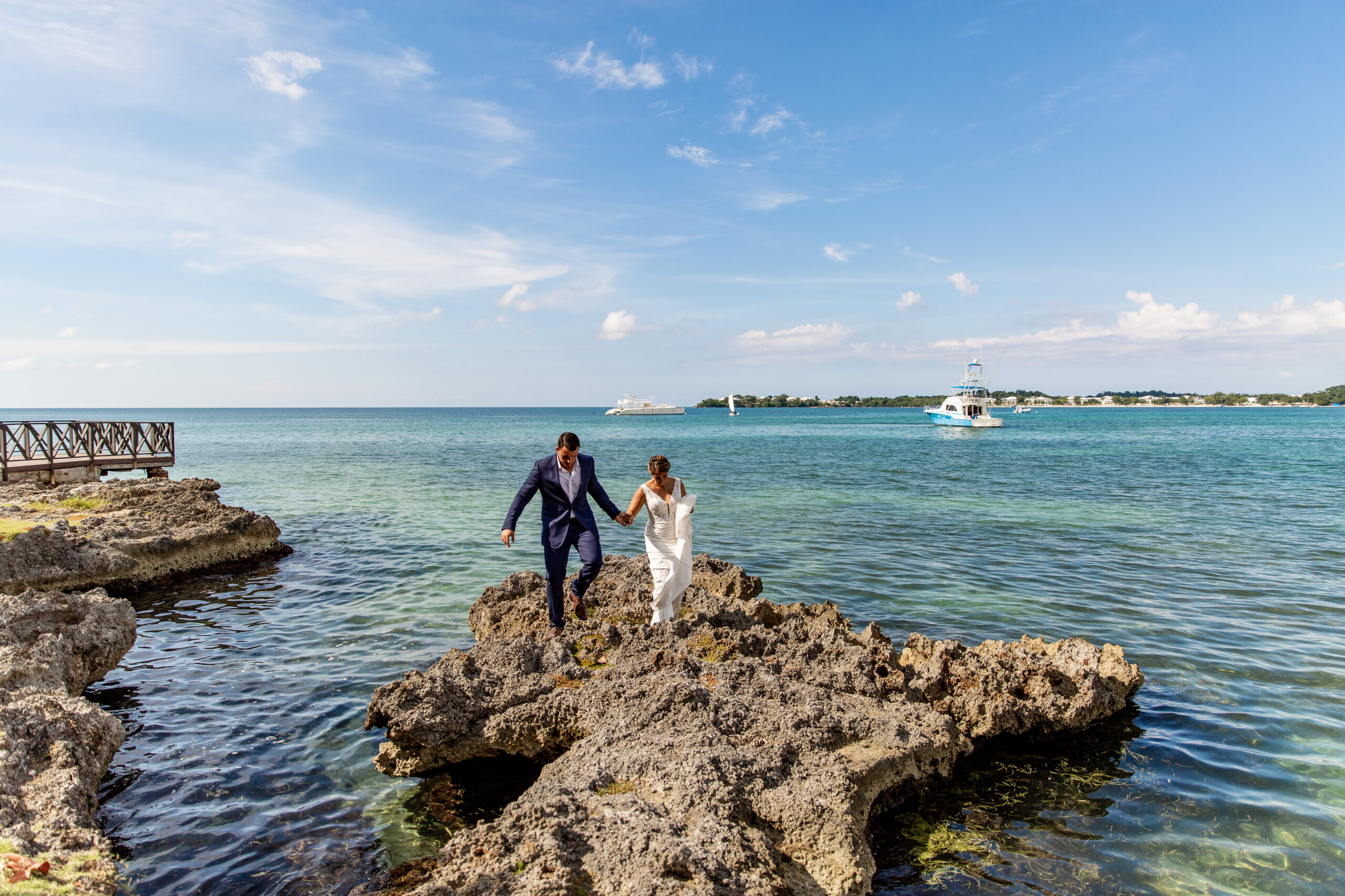 Bride and groom hold hands as they walk along reef for their bride and groom portraits at their Jamaican destination wedding