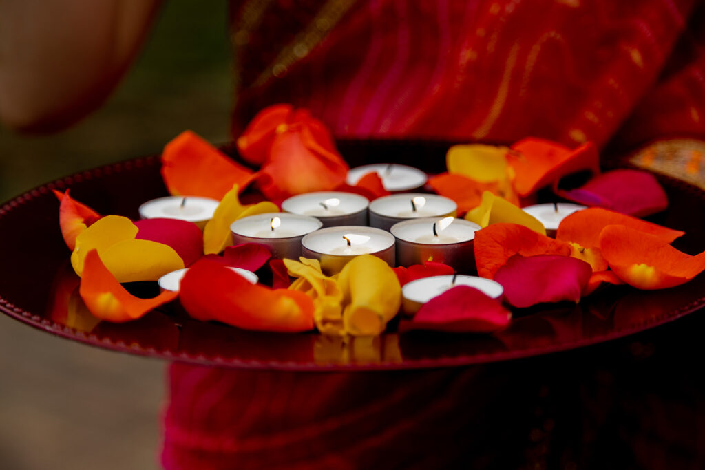 Up-close photo of traditional Indian candles and vibrant flower petals used in wedding ceremony at Northern Virginia garden venue