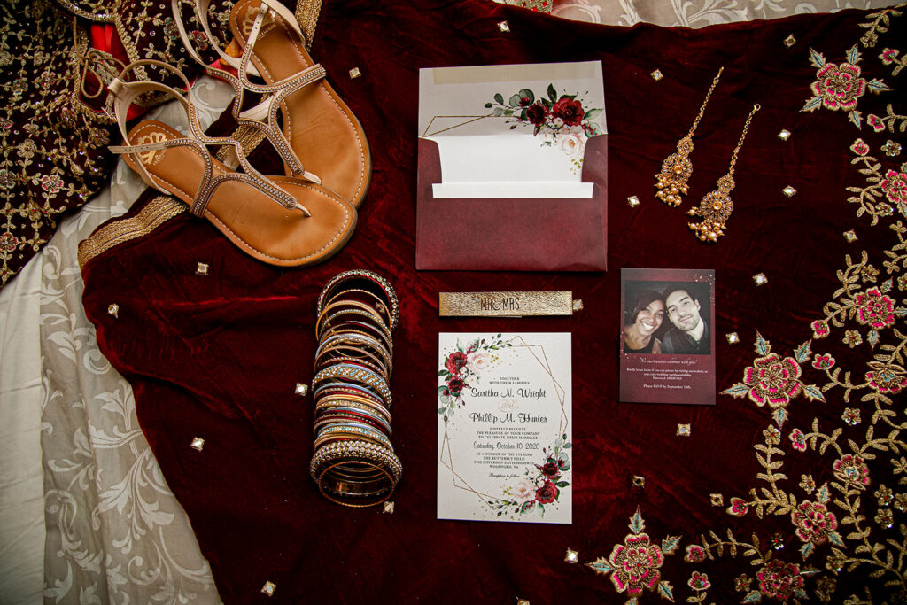 Flat lay of wedding invitation suite and cultural details styled with florals for an Indian-American wedding in Northern Virginia