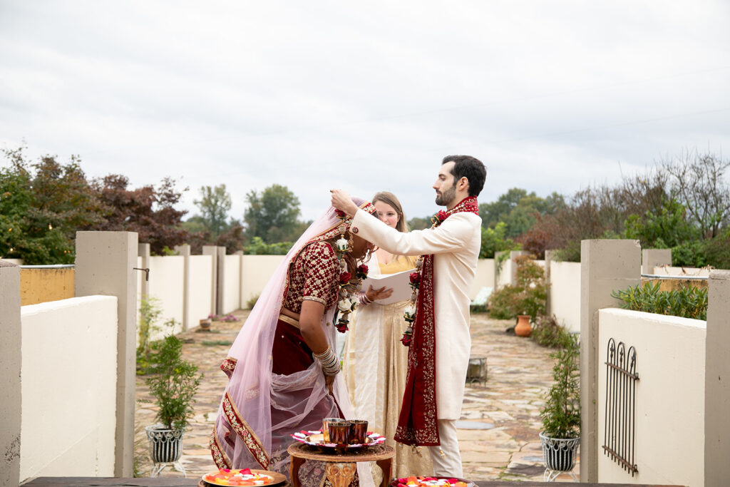 Bride and groom participating in traditional Indian wedding rituals surrounded by floral decor at Northern Virginia garden venue