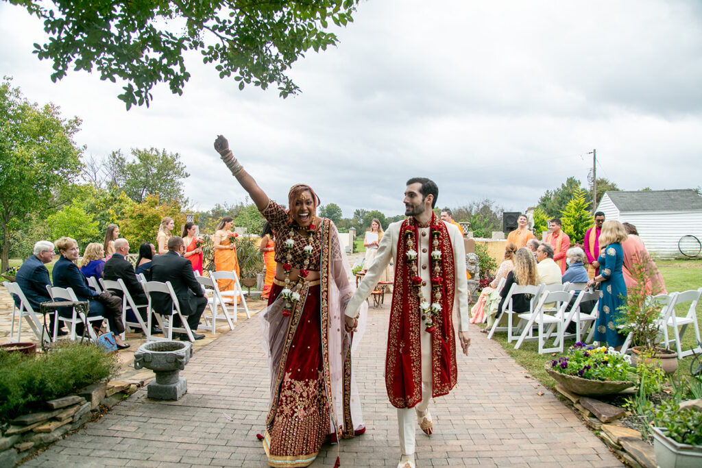 Bride and groom beaming as they walk back down the aisle hand-in-hand after saying 'I do' at their vibrant outdoor Northern Virginia wedding