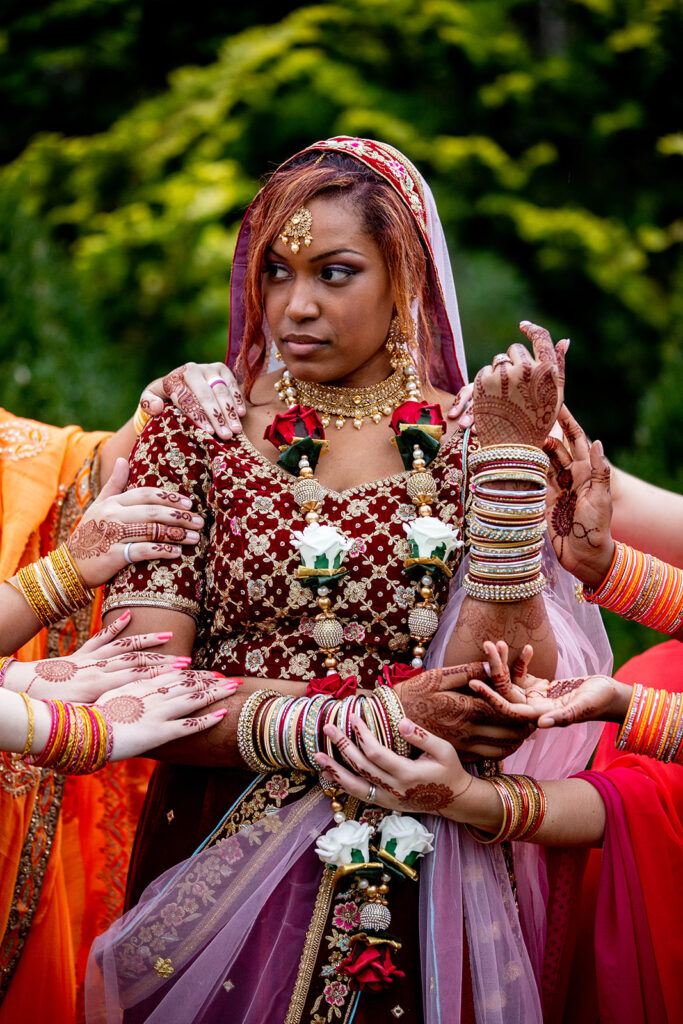 Cultural bridal portrait highlighting fresh henna on bridesmaids’ hands encircling the bride at outdoor Virginia wedding