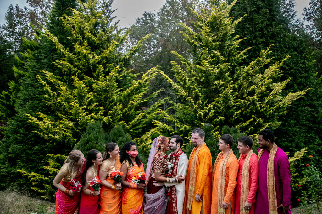 Bridal party surrounding bride and groom with joyful energy in colorful outdoor garden wedding in Woodford, VA