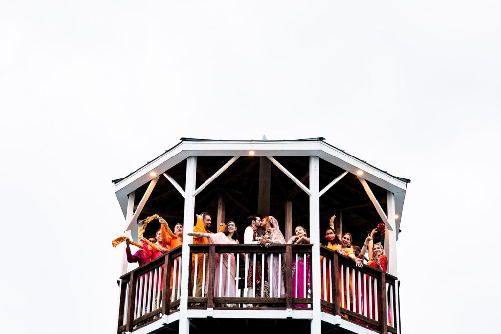 Bridal party joyfully celebrating the bride and groom kissing post a northern Virginia wedding ceremony