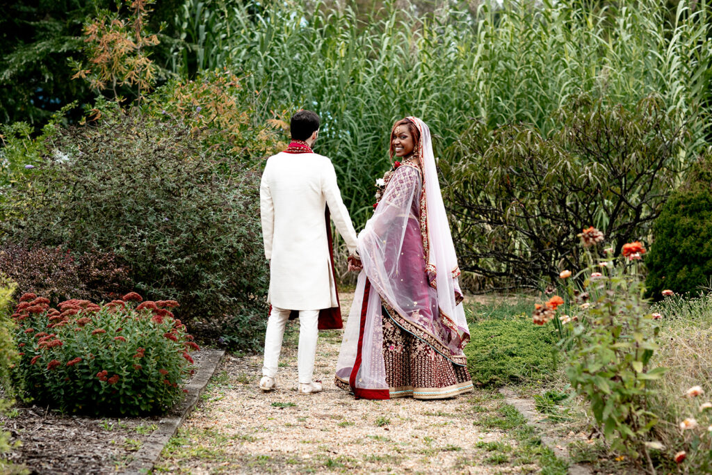 Romantic wedding photo of bride and groom walking hand-in-hand through the garden during their Northern Virginia celebration