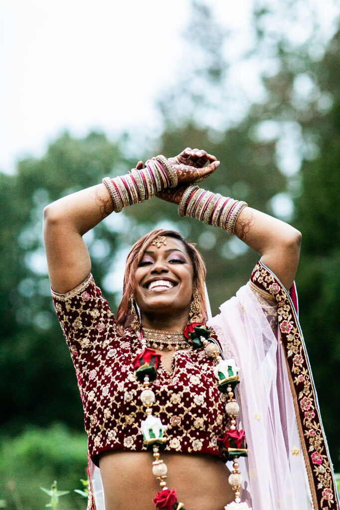 Stunning bride Saritha laughing during garden bridal portraits in vibrant sari with cultural jewelry