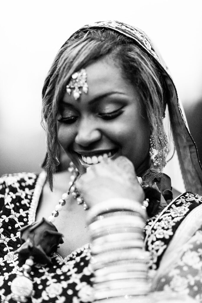 Close-up of bride’s radiant smile and intricate Indian wedding jewelry during outdoor portraits in Woodford, VA"
