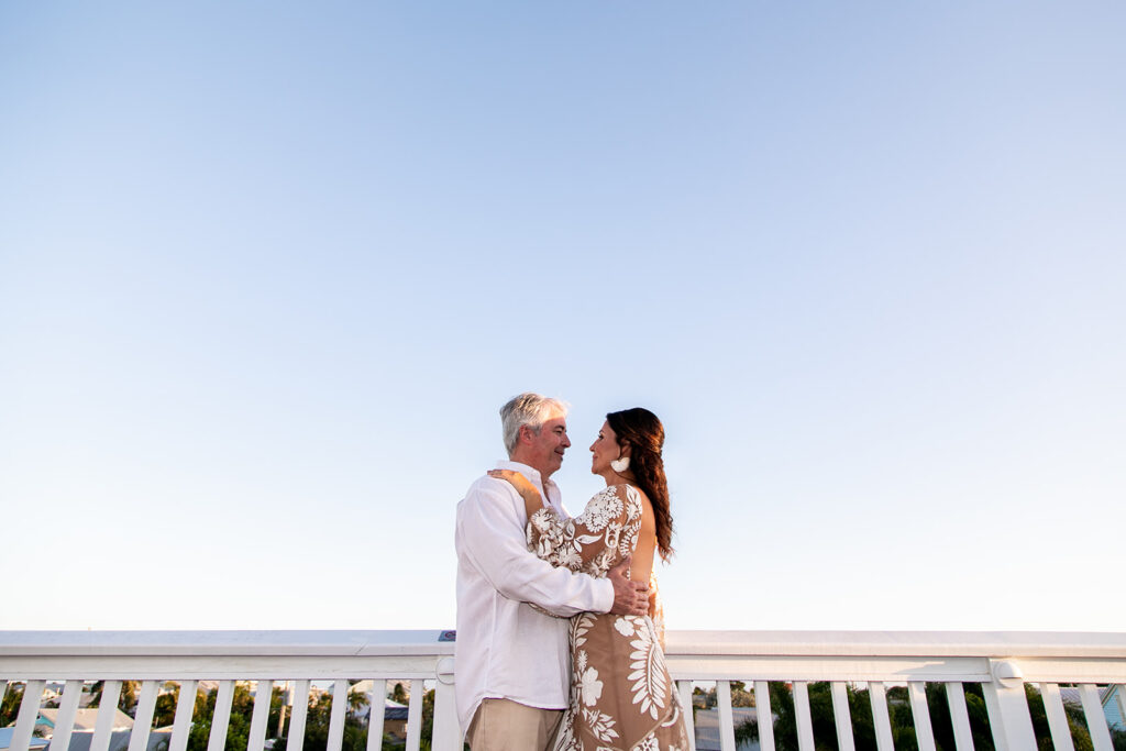 Sunset rooftop photo of the bride and groom framed by warm pastel skies.
