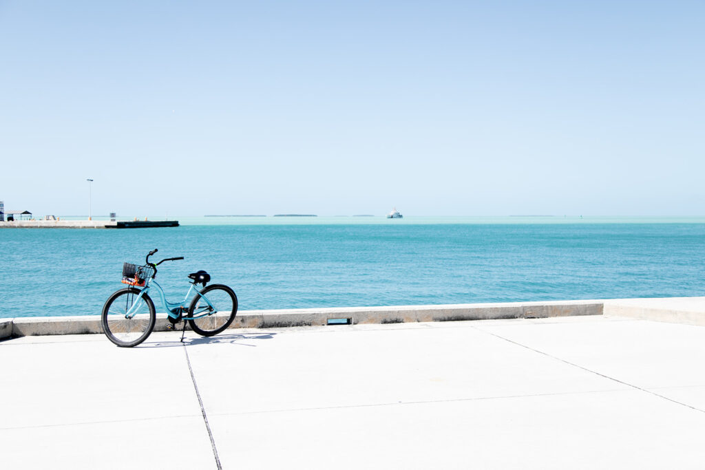 A bike parked along the dock next to the ocean in Key West