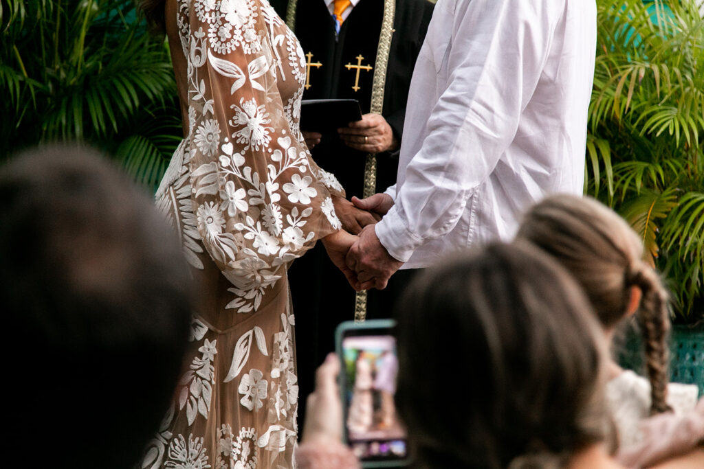 Close-up of hands clasped during the vow exchange.