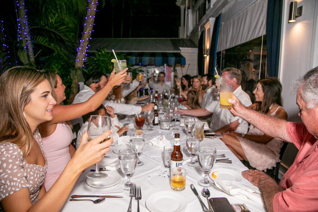 Guests raising a glass and giving a cheers during a spirited toast under twinkle lights.