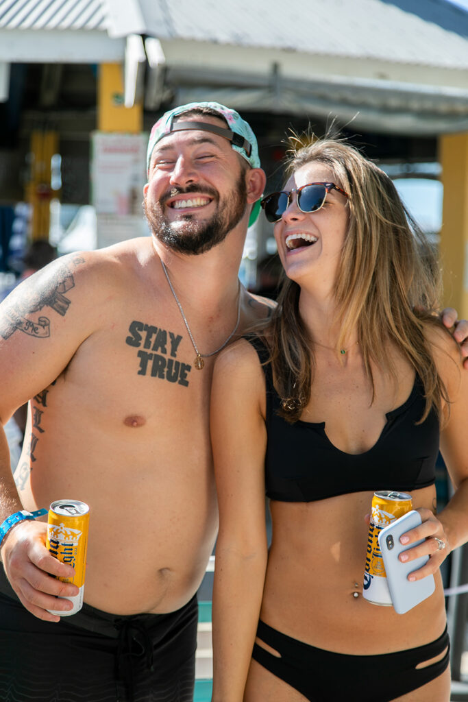 Family members laughing and lounging by the pool with tropical drinks in hand.