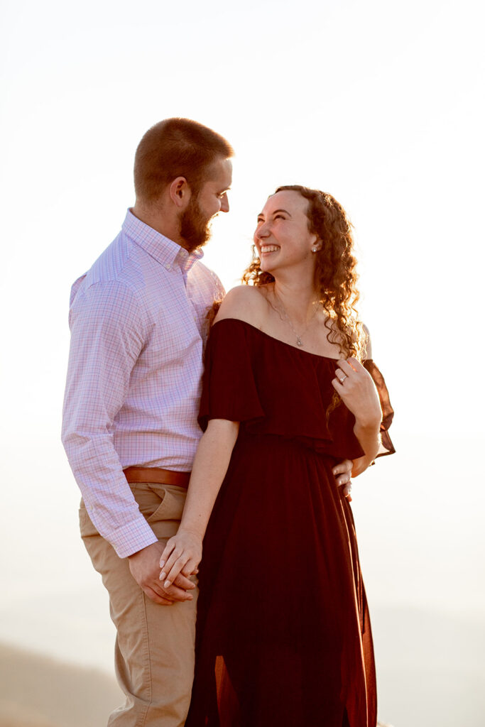 Engaged couple holding hands and smiling at each other during their formal mountain engagement session in Shenandoah
