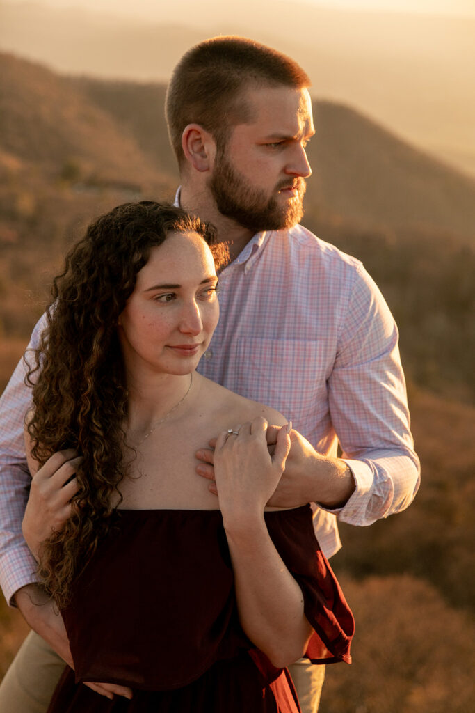 Bride-to-be laughing as fiancé kisses her neck during warm sunset engagement session in Shenandoah