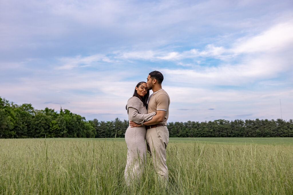 Newly engaged couple embracing during an engagement session in an open field near Washington DC
