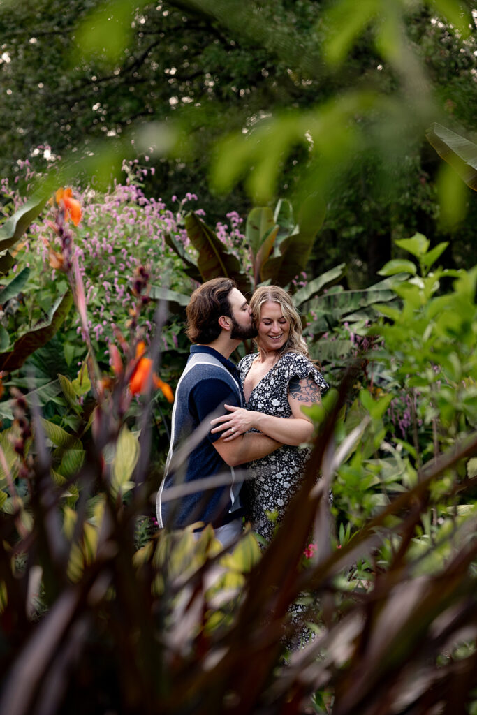 Surprise proposal engagement photos taken through lush garden foliage at Meadowlark Botanical Gardens in the DC area