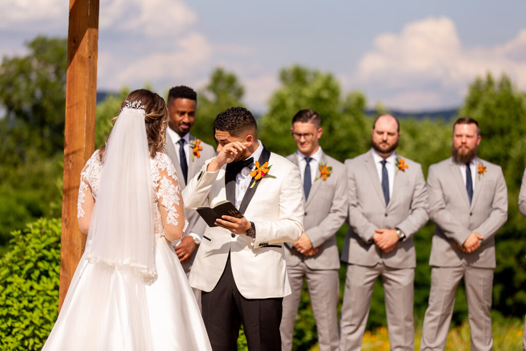 Groom wiping away tears while reading his vows during the ceremony.