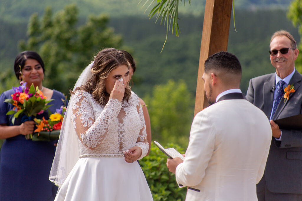 Bride holding back tears while listening to the groom read his vows.