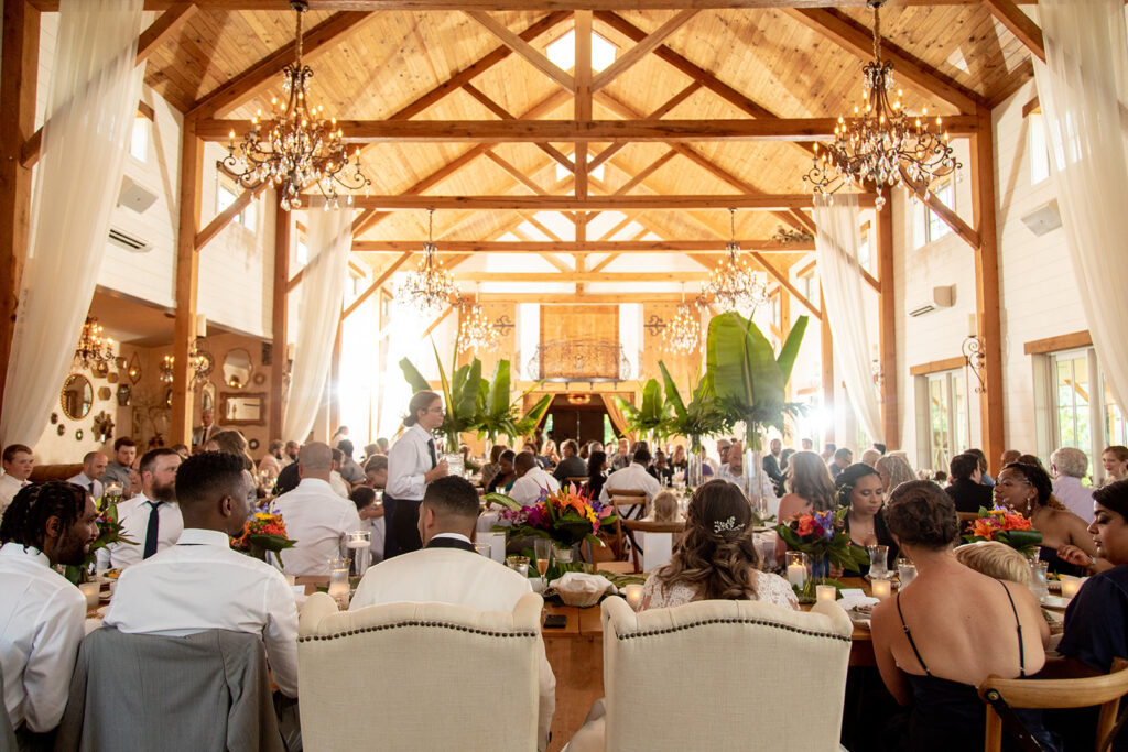 Wide view of the reception dinner at The Seclusion with chandeliers and tropical décor.