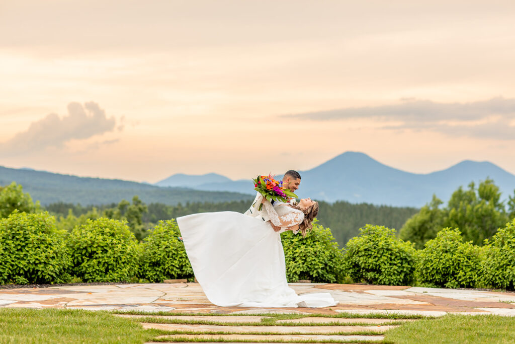 Groom dipping bride during dramatic sunset at golden hour at The Seclusion with the blue ridge mountains in the background.