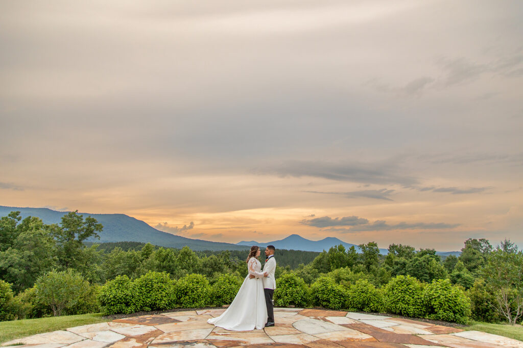 Bride and groom standing on a stone patio at The Seclusion during sunset, surrounded by Blue Ridge Mountain views.