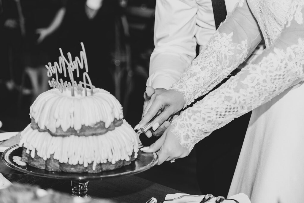 Bride cutting the bundt wedding cake during the reception, black-and-white image.