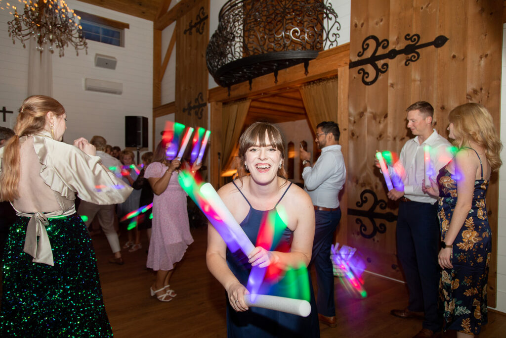 Guests dancing with colorful glow sticks on the dance floor.