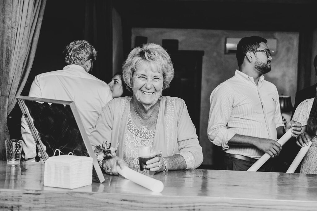 Guest smiling at the bar during the reception, black-and-white image.