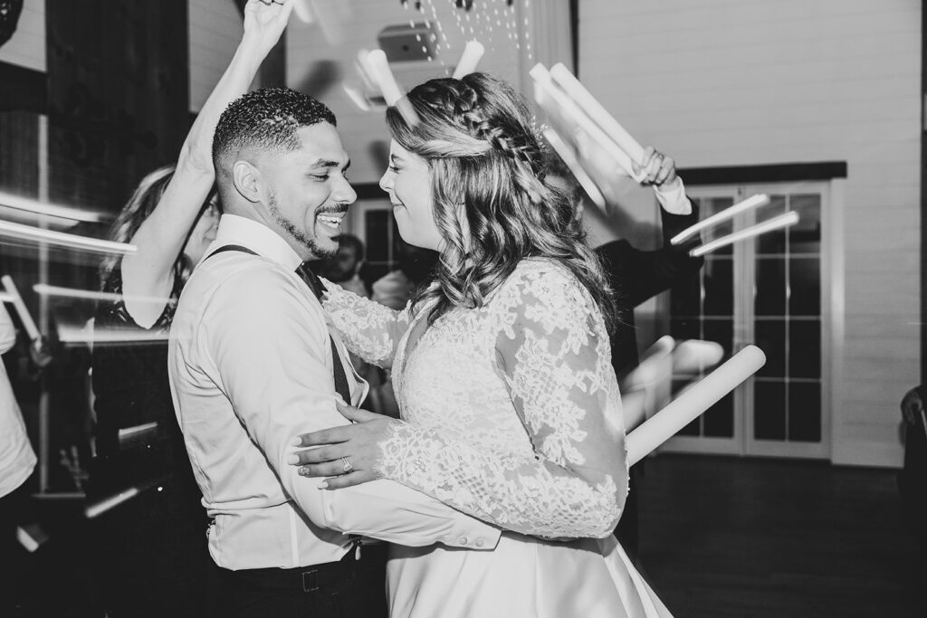 Bride and groom dancing closely together under reception lights.