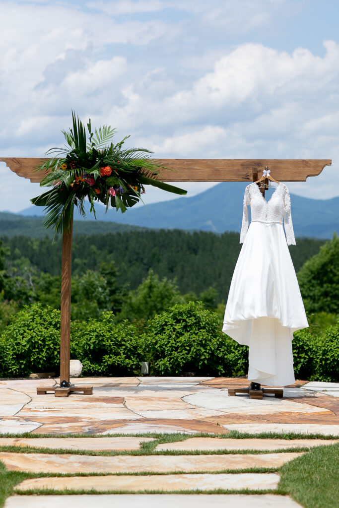 Wedding dress hanging from a wooden ceremony arch with mountain views at The Seclusion.