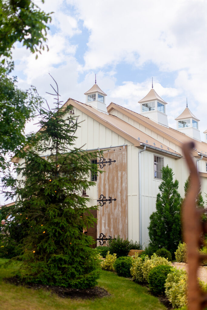 Exterior of The Seclusion in Lexington, VA with white barn-style architecture and lush summer greenery.