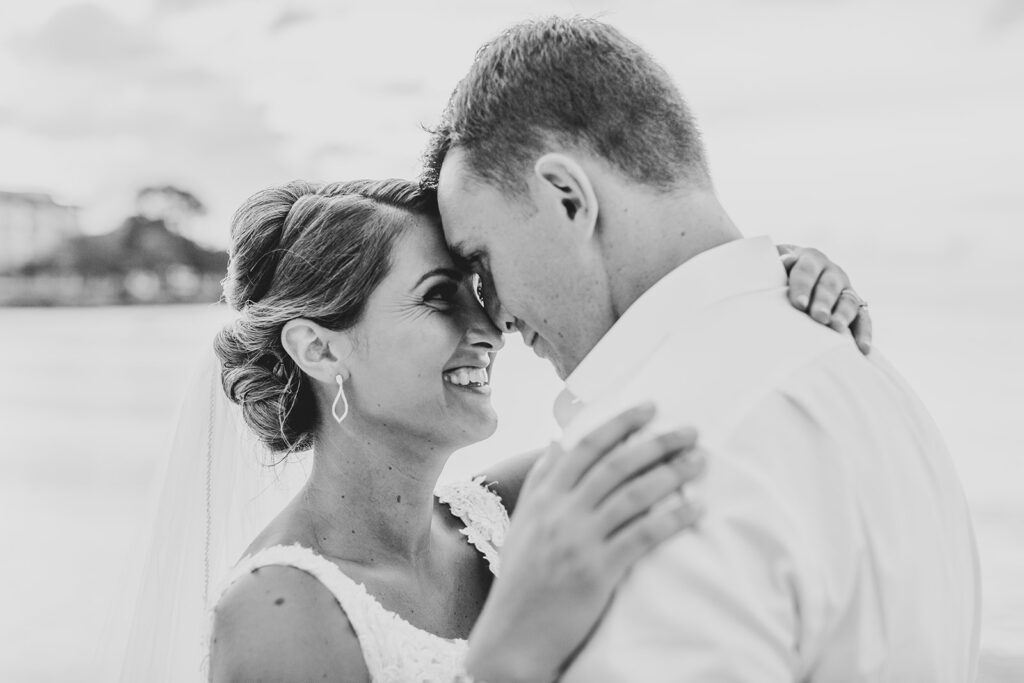 Close-up of the couple smiling and touching foreheads on the beach.