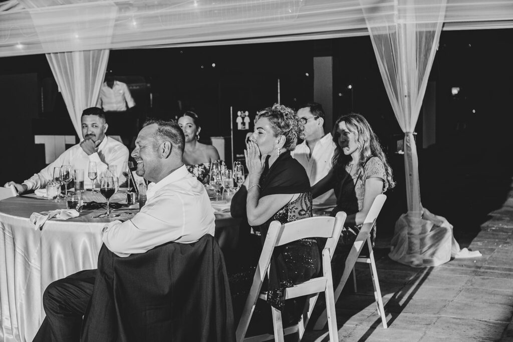 Wedding guests watching speeches and laughing during the reception dinner.