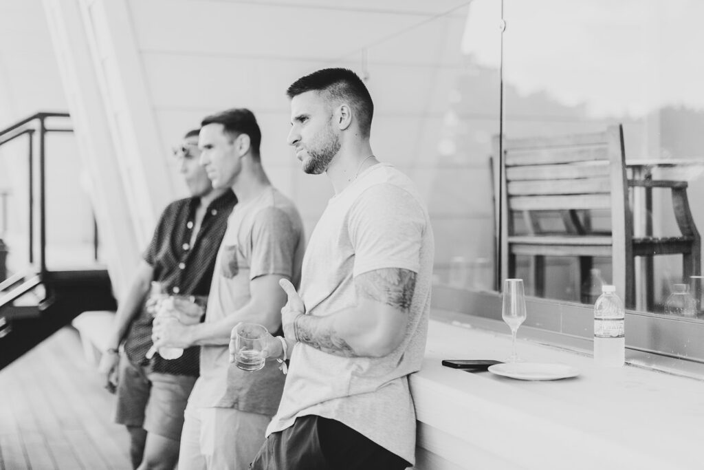 Black and white photo of the groom and groomsmen relaxing on the balcony during getting-ready time.