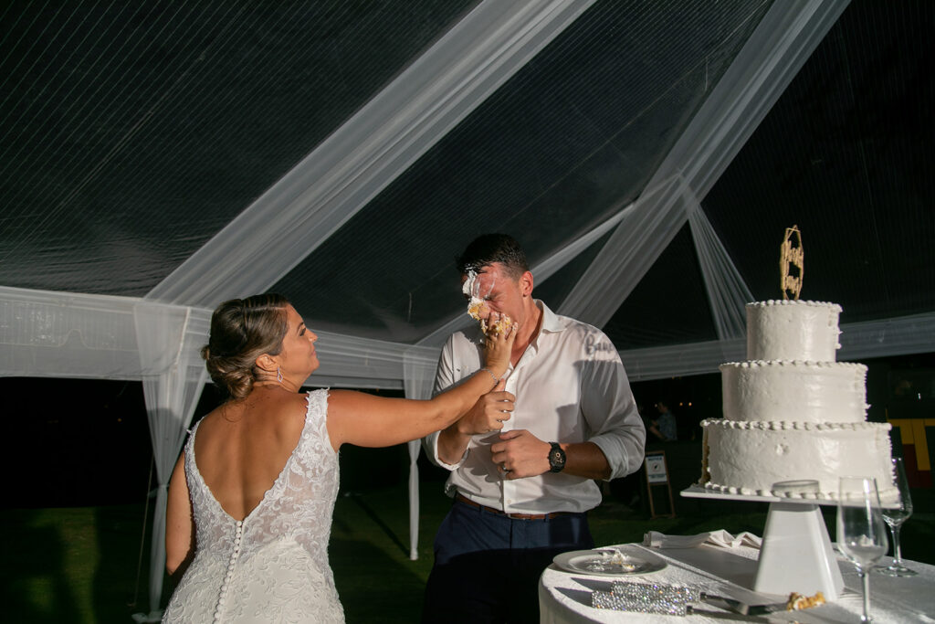 Bride smashes cake into grooms face.