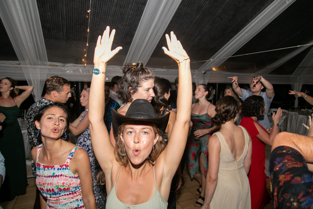 Guest lifting her arms and dancing energetically at the reception.