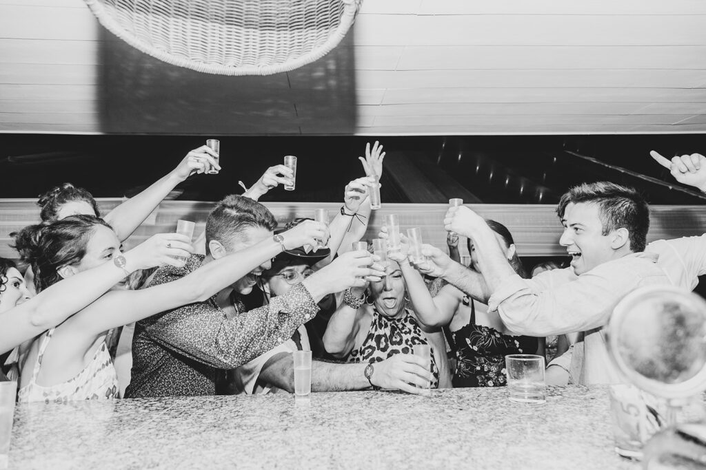 Guests crowding around the bar taking shots together in celebration.