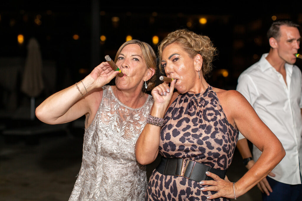 Mother of the bride and mother of the groom charing a moment with hand rolled cigars at a destination wedding.