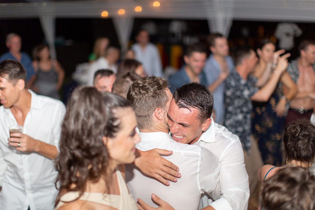 Groom hugging guests during the late-night reception festivities.