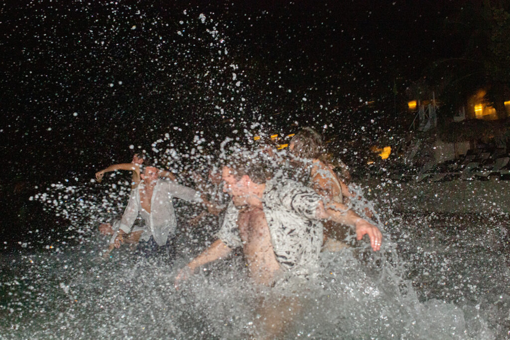 Wedding guests splashing water during a nighttime beach celebration at the Royalton Negril resort.
