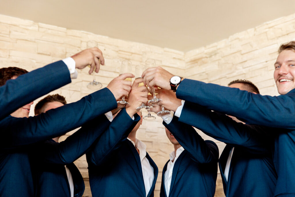 Groom and groomsmen raising glasses together for a final toast before the ceremony.