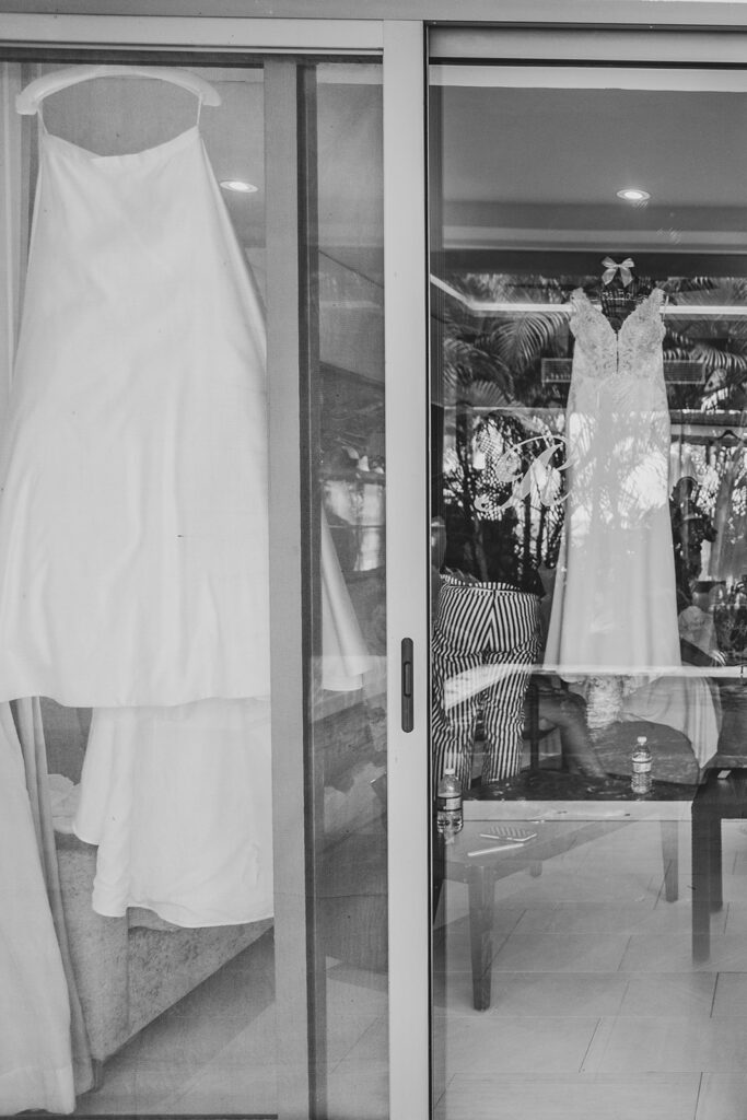 Black and white photo of the bride’s wedding dress hanging inside a modern resort room at Royalton Negril.