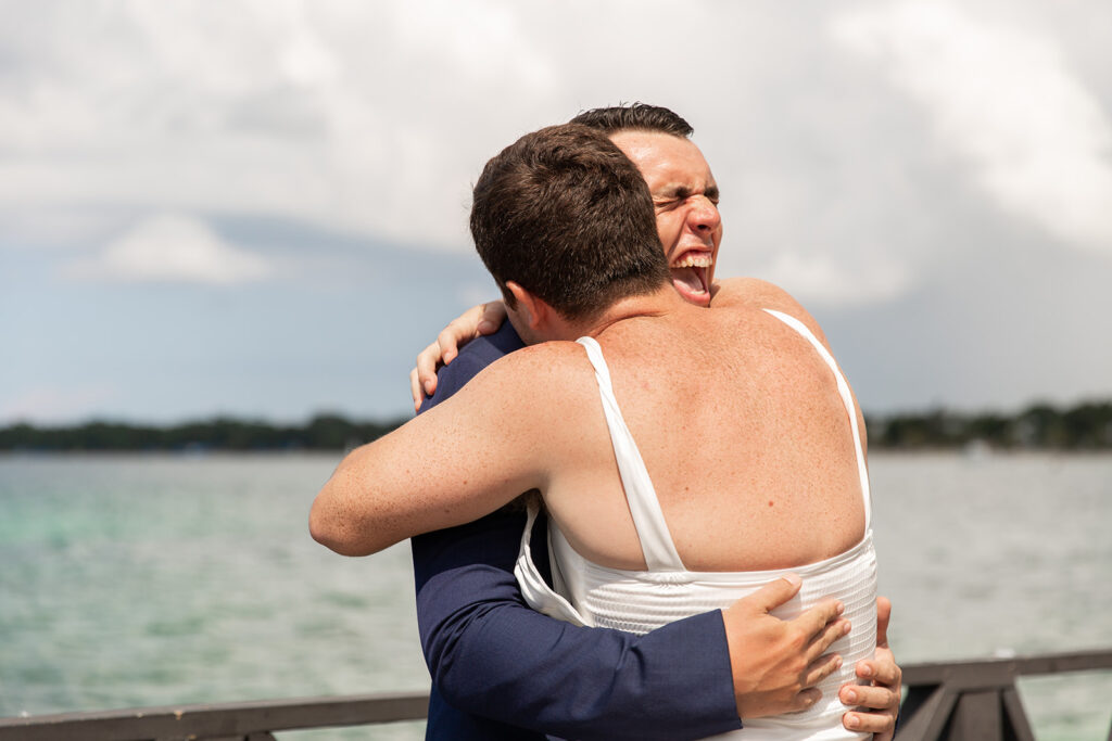 Groom hugging his friend dressed in a wedding gown during the playful faux first look.