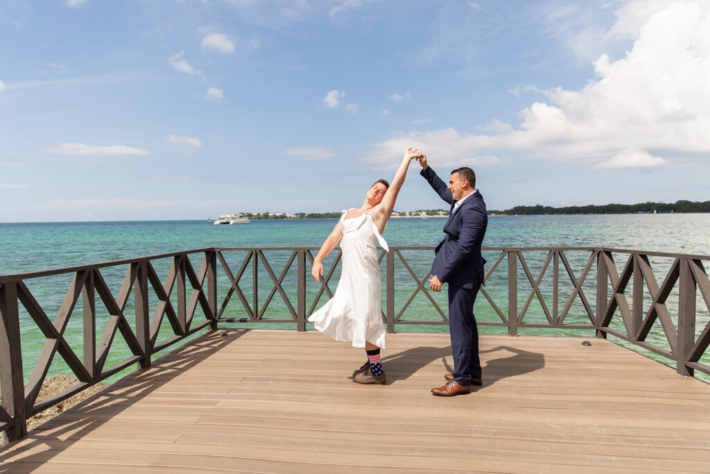 Friend in a wedding gown twirling as the groom spins them during the faux first look moment.