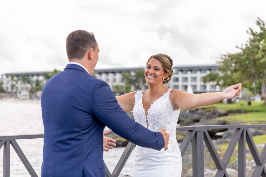 Bride reaching her arms out to the groom as he smiles during the first look.