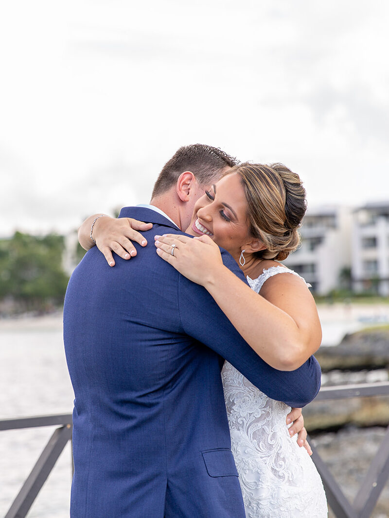 Bride and groom embracing during their emotional first look on the oceanfront dock.